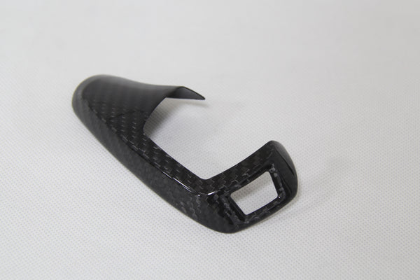carbon fiber gear shifter cover laying down on white background