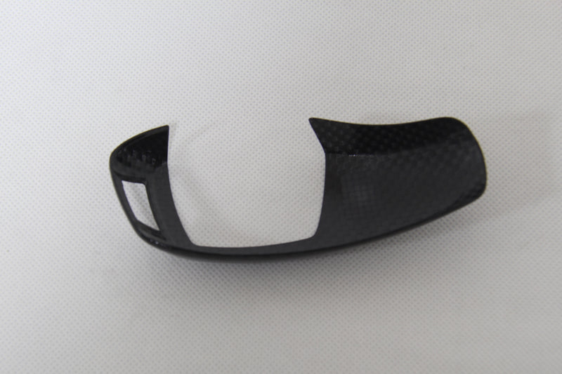 carbon fiber gear shifter cover laying down on white background
